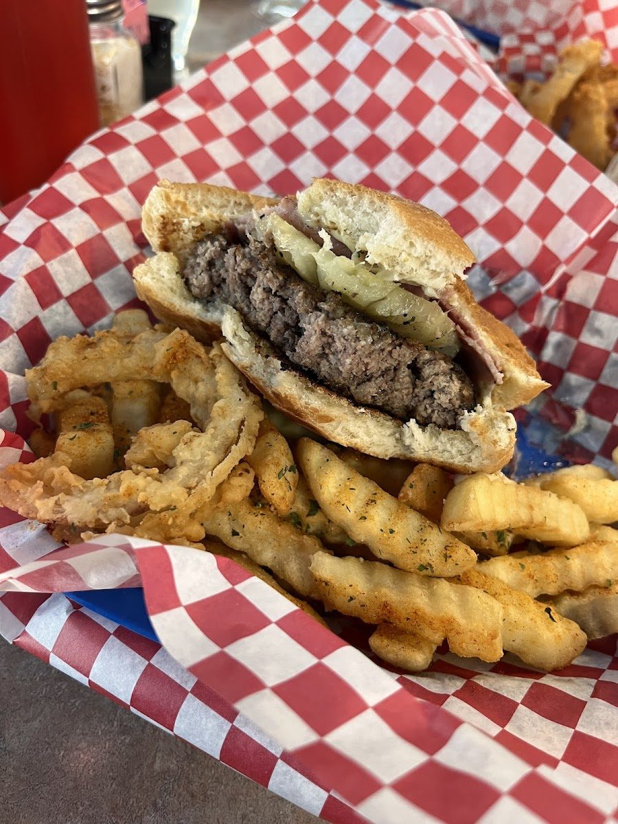 An 8oz burger in a red checkered basket with homemade onion rings and fries