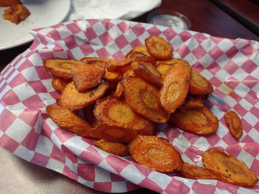 A basket of golden fried carrot slices on checkered paper