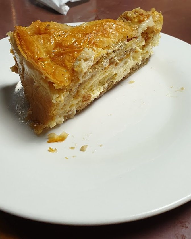 A slice of galaktoboureko, golden filo pastry with semolina custard, on a white plate