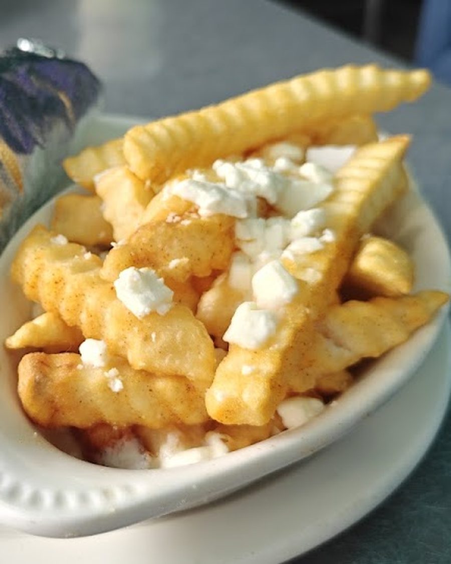 A gyro on a plate next to a bowl of french fries topped with melted feta cheese