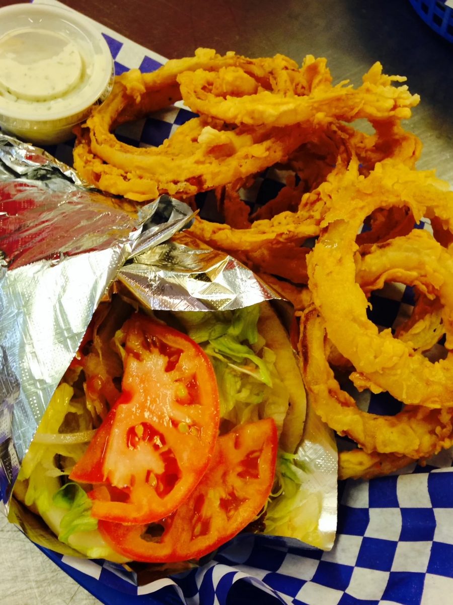 A basket of homemade battered onion rings with a foil-wrapped gyro